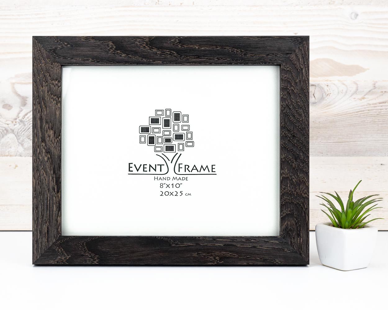 A black solid oak hardwood photo frame with a clear acrylic glass cover, displaying a logo and the text 'EventFrame' on the front, placed on a wooden surface with a potted plant to the side. Handmade Picture Frame from Black Oak Hardwood, Wooden Photo Frame, Custom Sizes A5 A4 A3 A2 A1 6x8 8x8 8x10 10x10 8x12 11x14 18x24 20x30